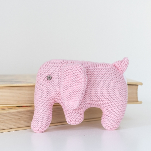 Pink Organic Cotton Knitted Elephant Baby Rattle in front of books lay flat
