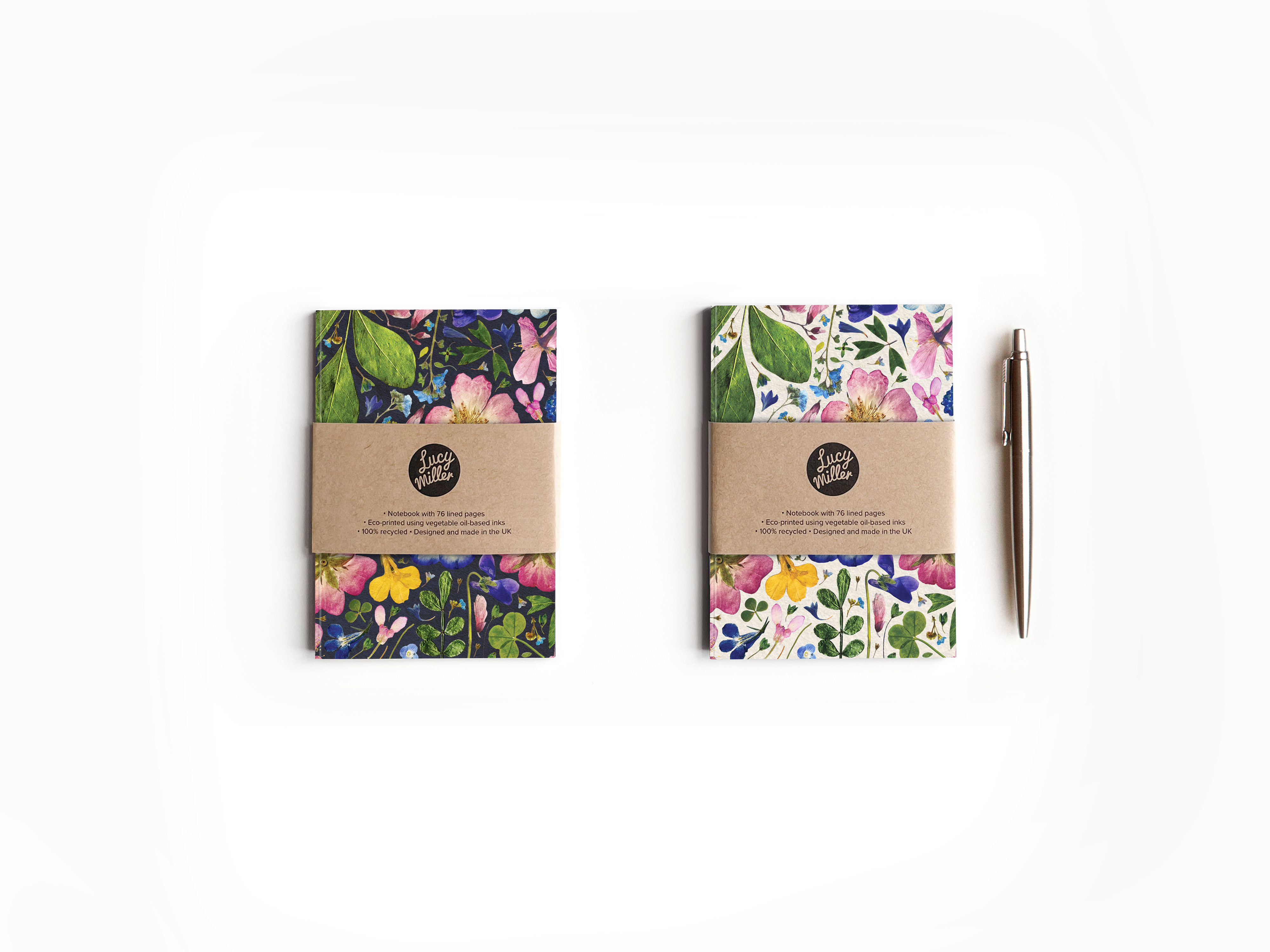 A6 Floral Notebooks in Natural and Ink Two A6 recycled notebooks with a pressed flower design. One with a light, natural background. One with a dark, ink background. The notebooks lie on a white background, with a pen to the side.