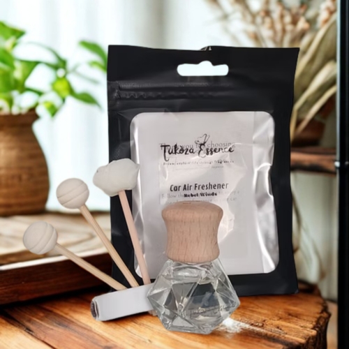 Rebel Winds car air freshener displayed on a rustic wooden table with three diffuser reeds – natural and elegant presentation